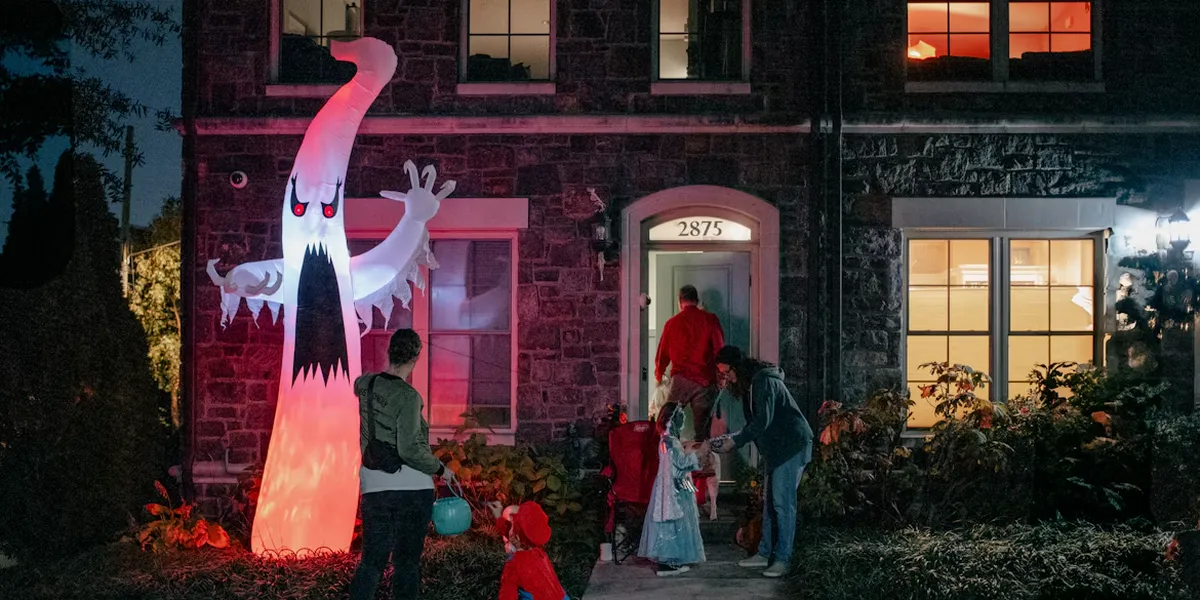 Kids in costumes trick-or-treating next to a giant inflatable ghost