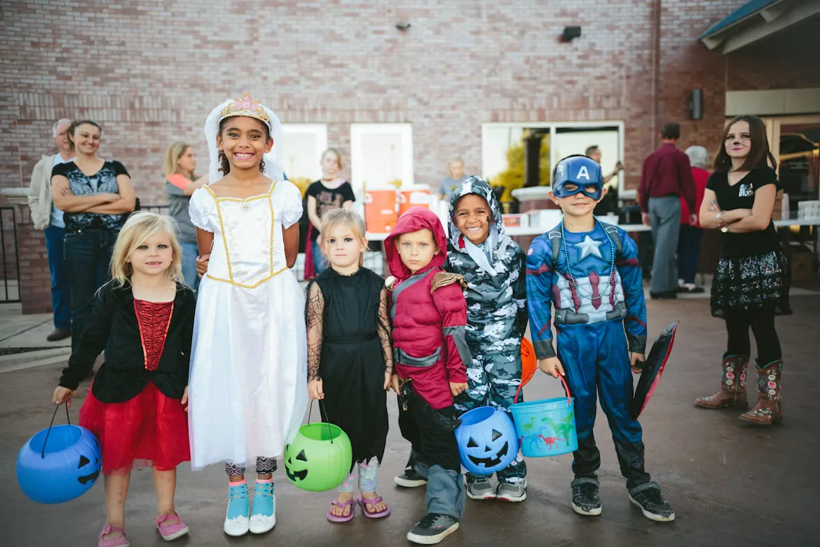 Kids in Halloween costumes holding pumpkin candy buckets