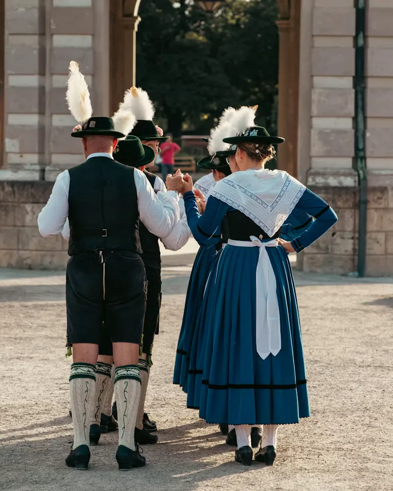 People in traditional Bavarian costumes and feathered hats at an Oktoberfest