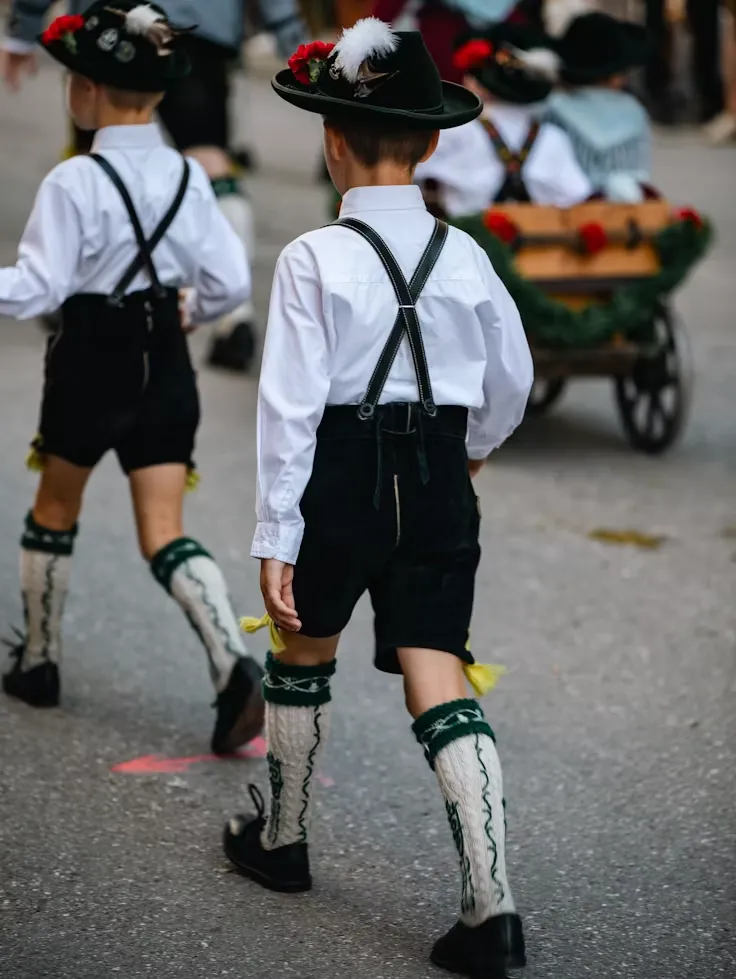 Two kids in lederhosen and knee socks walking in a festival parade