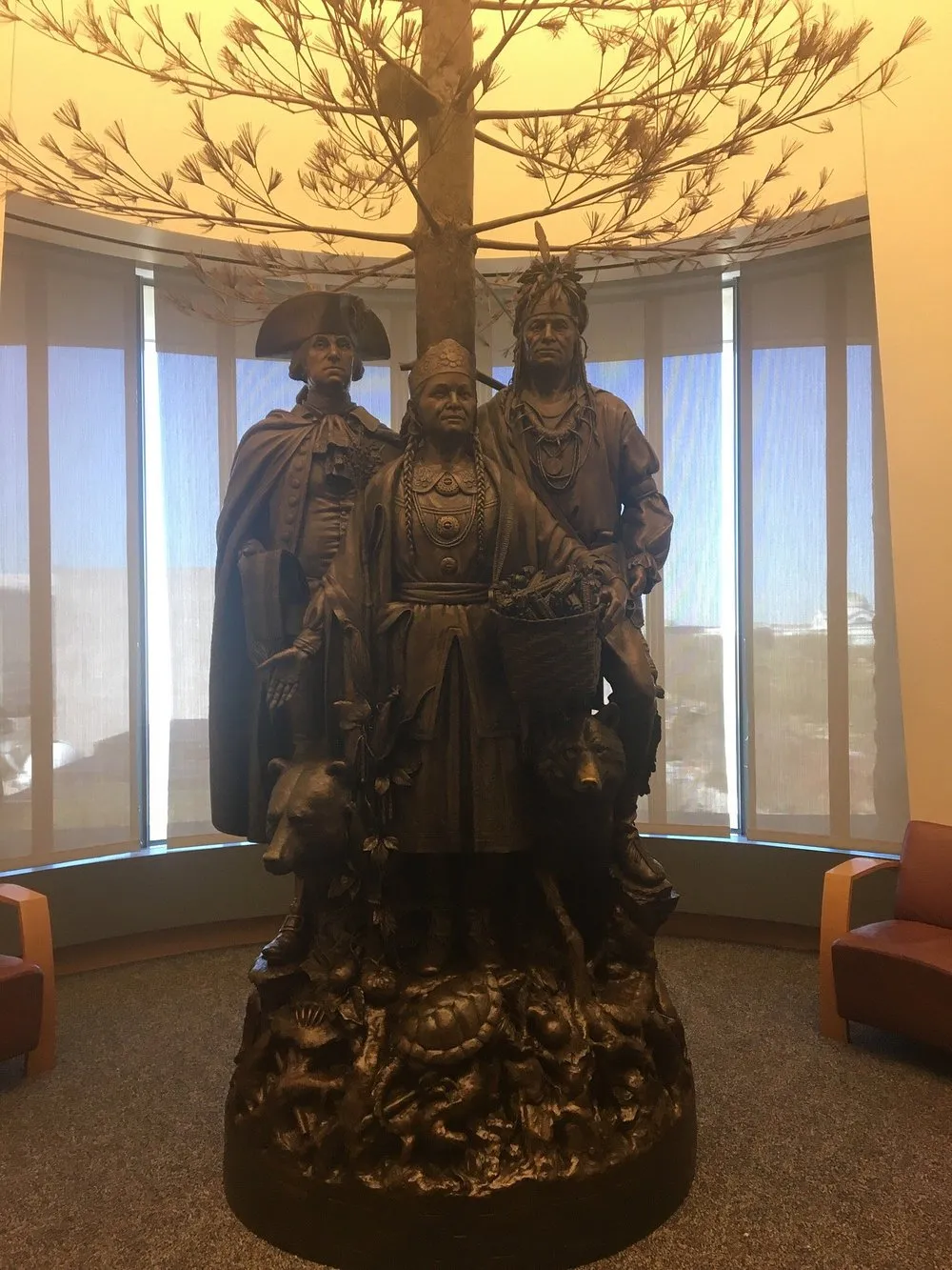 A bronze sculpture of a Native family displayed in a museum gallery