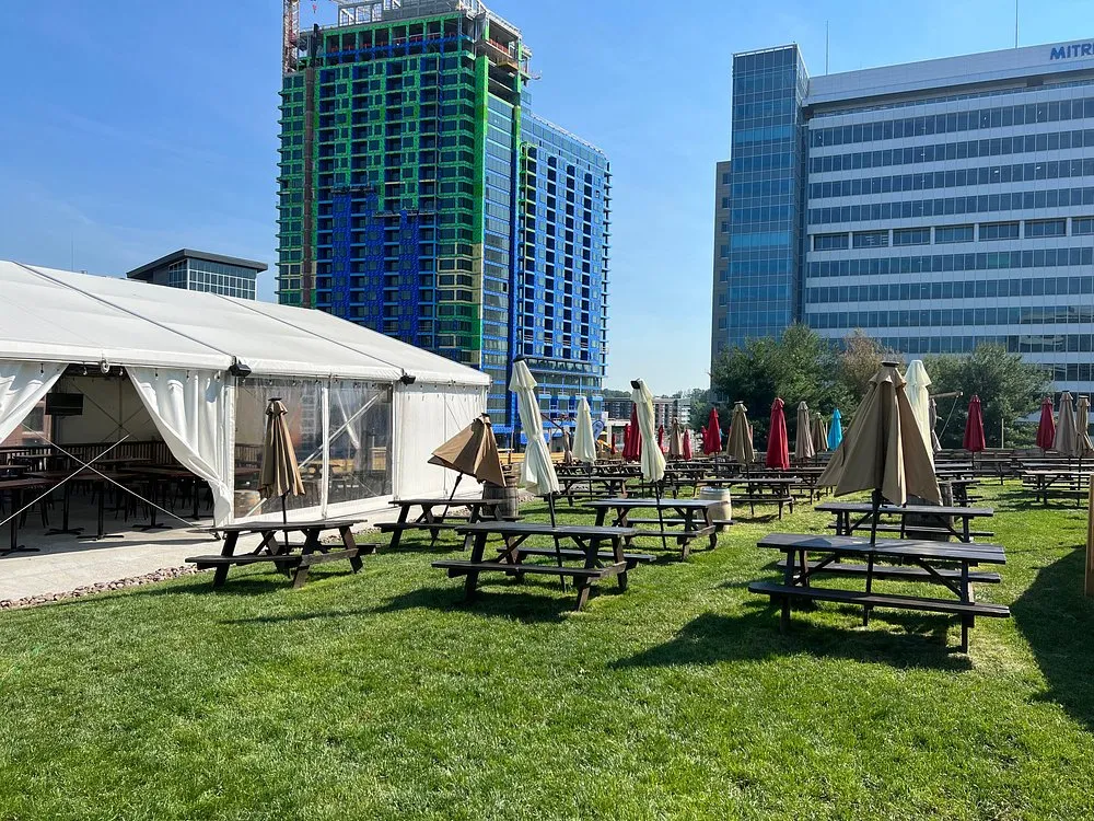 Picnic tables on a grassy lawn next to white tents under a blue sky