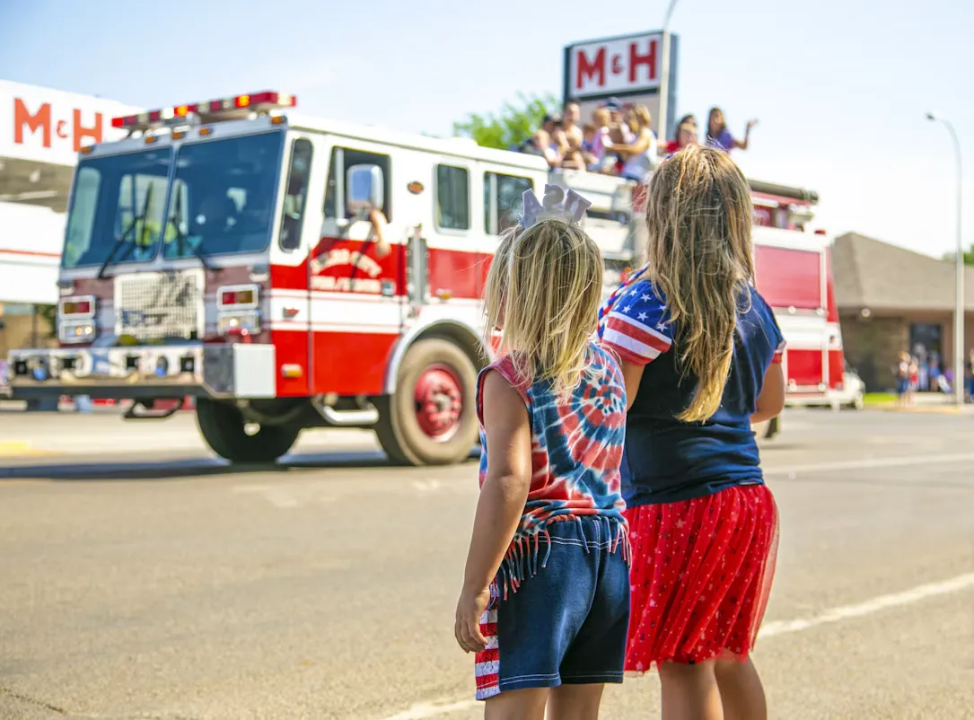 Two little girls watching a red fire truck drive past
