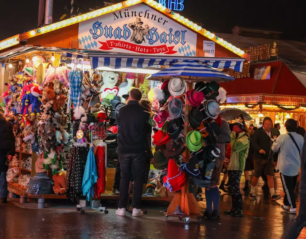 A brightly lit Oktoberfest stand selling hats and souvenirs in the evening